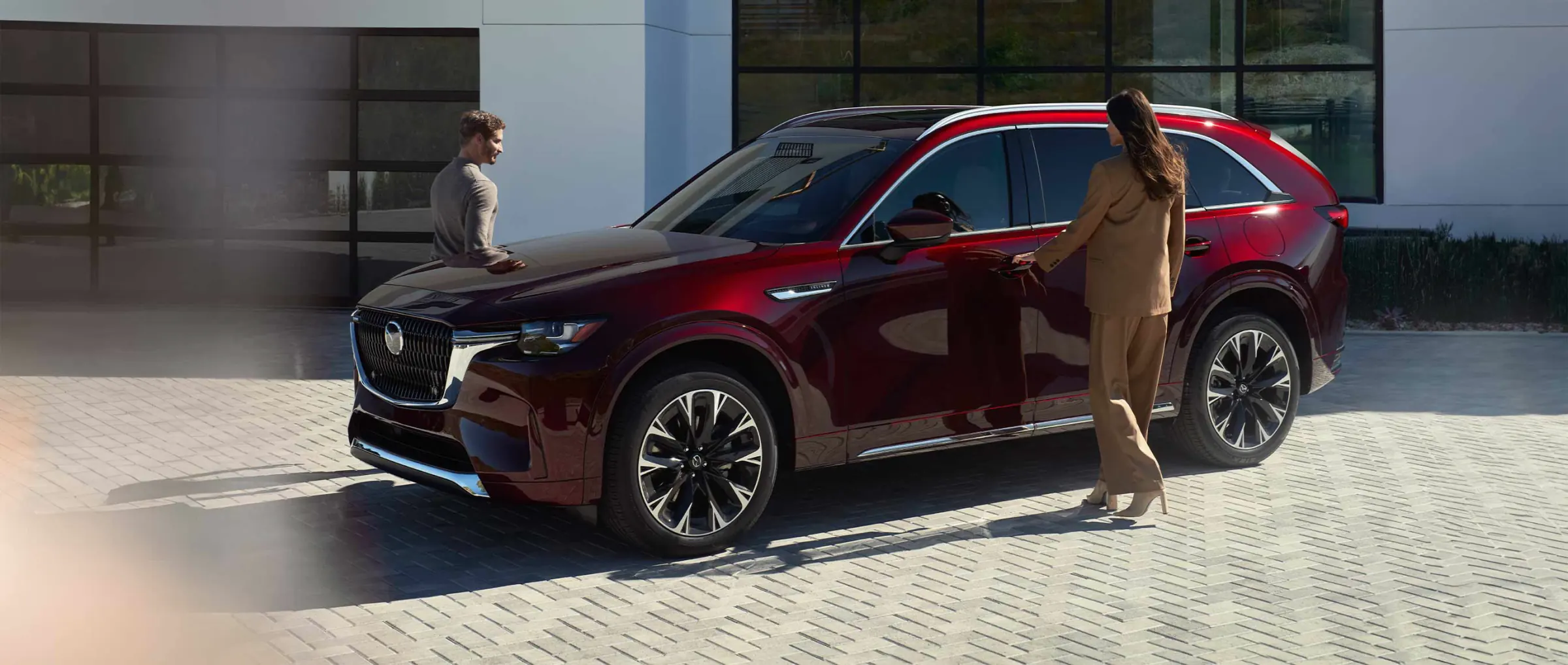 Una pareja junto a un CX-90 rojo