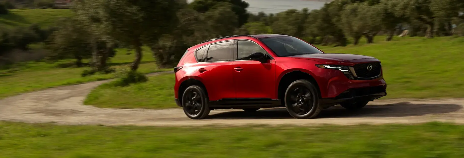 Un CX-5 rojo recorre un camino de tierra con tracción i-Activ AWD